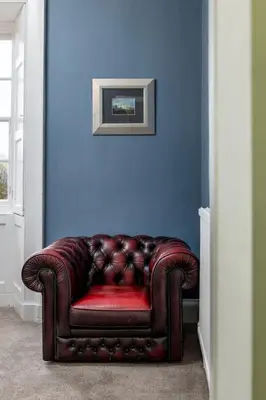 a brown leather couch sitting against a blue wall at Elegant 3 Bed Apartment in Stirling Near Free Parking and Hill Views in Stirling