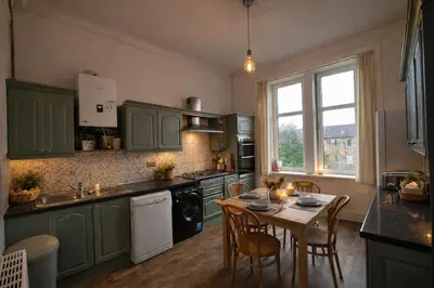 a kitchen with green cabinets and a table with chairs at Contractors and Guests Grand 3 Bedroom Central Free Parking Fully equipped in Glasgow