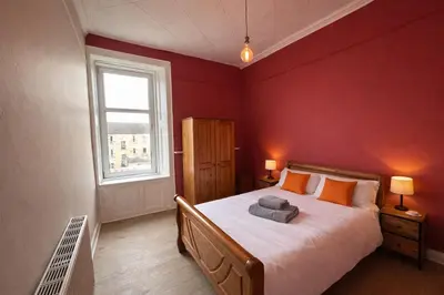 a bedroom with a large bed with red walls at Contractors and Guests Grand 3 Bedroom Central Free Parking Fully equipped in Glasgow