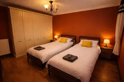 two twin beds in a room with two lamps at Comfortable 3 Bed Home with Garden & Parking Stylish Family Contractor in Newton Mearns