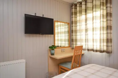 a bedroom with a desk and a television on the wall at Heather Lodge with Hot Tub in Hunters Quay