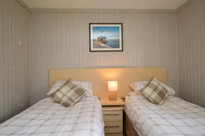 a bedroom with two beds and a lamp on a night stand at Heather Lodge with Hot Tub in Hunters Quay