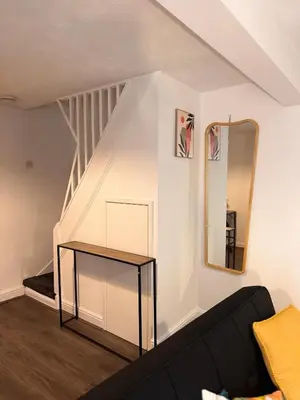a living room with a black couch and a mirror at Stay With OG - Modern Two-Bedroom Apartment in Moffat