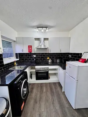 a kitchen with white cabinets and a washer and dryer at Stay With OG - Modern Two-Bedroom Apartment in Moffat