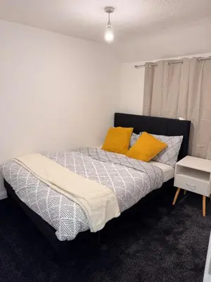 a bedroom with a bed with yellow pillows on it at Stay With OG - Modern Two-Bedroom Apartment in Moffat