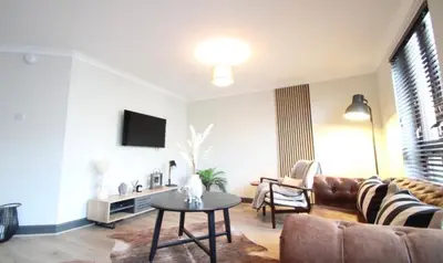a living room with a couch and a table at Stylish 2 Bed Duplex with Balcony & Parking Merchant City in Glasgow
