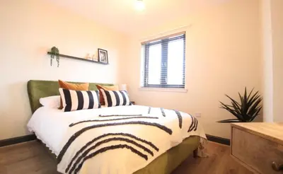 a bedroom with a bed and a window at Stylish 2 Bed Duplex with Balcony & Parking Merchant City in Glasgow