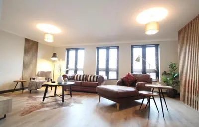a living room with a couch and tables and windows at Stylish 2 Bed Duplex with Balcony & Parking Merchant City in Glasgow