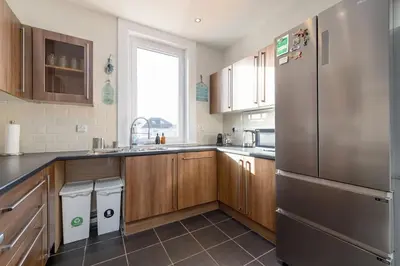 a kitchen with wooden cabinets and a stainless steel refrigerator at Barnton Grove Getaway in Edinburgh