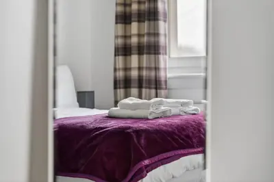 a reflection of a bed with towels on a purple blanket at Troon Golf by the Sea in Troon