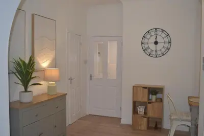a room with a clock on the wall and a table with a plant at Large 8 Bed Group and Contractor Accommodation in Stirling