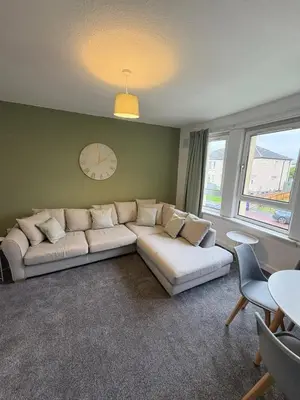 a living room with a couch and a clock on the wall at Home in Glasgow3BR -Ziplinks - Sleeps 6 G51 in Glasgow