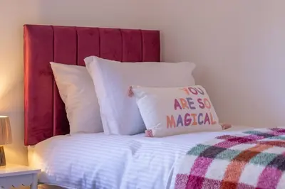a bed with a red headboard and a pillow at Betty's House - 3 bedroom in Coatbridge in Glenboig