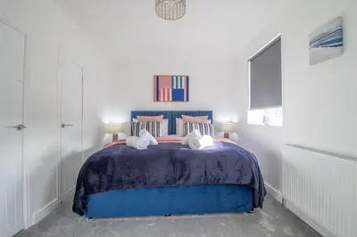 a bedroom with a blue bed with pink pillows at Betty's House - 3 bedroom in Coatbridge in Glenboig