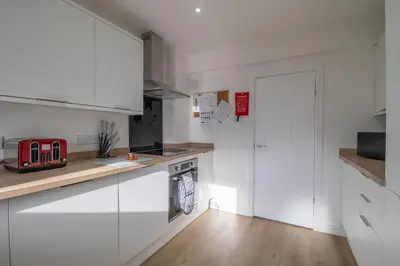 a kitchen with white cabinets and a refrigerator at Betty's House - 3 bedroom in Coatbridge in Glenboig