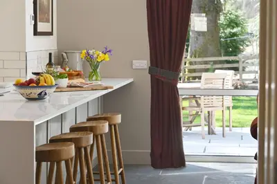 a kitchen with a counter with bar stools and a table at Kennels Cottage in Buchanty