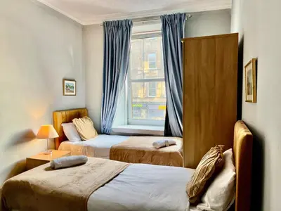 a hotel room with two beds and a window at Lovely Apartment by Meadows 1 in Edinburgh