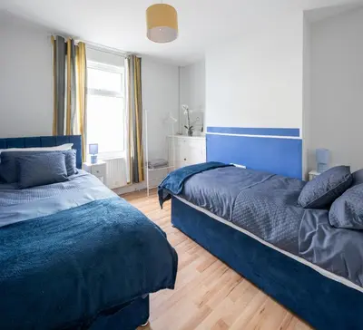 a bedroom with two beds with blue sheets and a window at 3 Bedroom house In Gloucester in Moffat