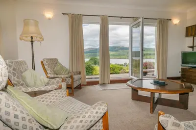 a living room with a couch and chairs and a television at Blarghour Farm Cottages in Ardchonnell