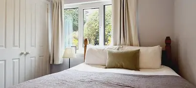 a bedroom with a bed with white pillows and a window at Elmbank Garden Apartment in Oban