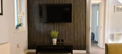 a living room with a tv on a wall at Elmbank Garden Apartment in Oban