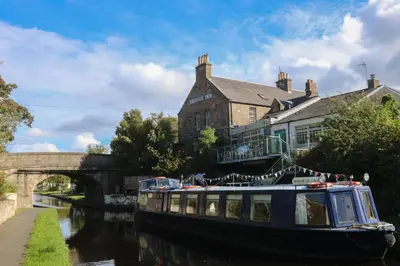 a boat on a river in front of a building at The Bridge Inn in Ratho