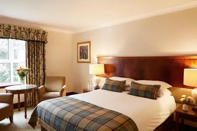 a hotel room with a bed and a chair at The Grange Manor in Grangemouth