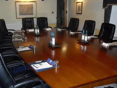 a conference room with a large wooden table and black chairs at The Grange Manor in Grangemouth