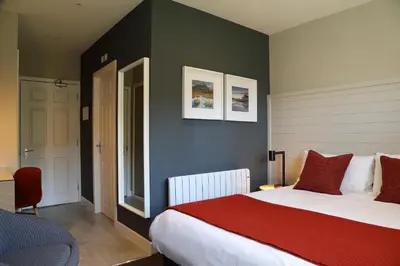 a bedroom with a large bed with a red blanket at The Isles of Glencoe Hotel in Glencoe