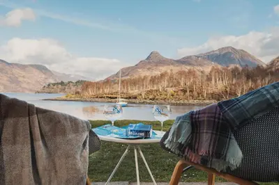 a table and chairs with a view of a lake at The Isles of Glencoe Hotel in Glencoe