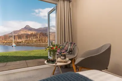 a room with a table and chairs and a large window at The Isles of Glencoe Hotel in Glencoe