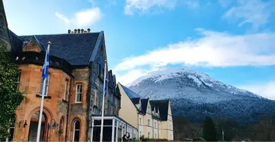 a building with people on top of it with a mountain at The Ballachulish Hotel in Glencoe