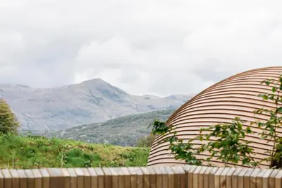 a large curved object with mountains in the background at RiverBeds - Luxury Wee Lodges with Hot Tubs in Glencoe