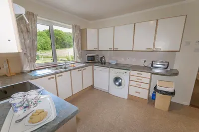 a kitchen with white cabinets and a washing machine at Blarghour Farm Cottages Overlooking Loch Awe in Ardchonnell