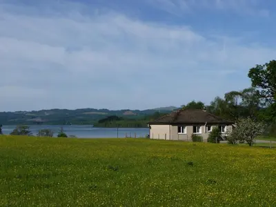 a house in a field with a field of flowers at Blarghour Farm Cottages Overlooking Loch Awe in Ardchonnell