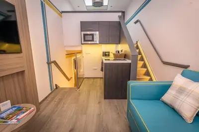 a living room with a blue couch and a kitchen at Court Residence Aparthotel in Linlithgow