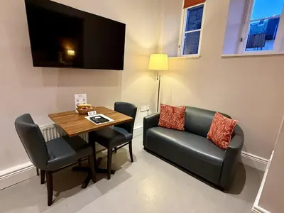 a dining room with a table and a chair and a television at Court Residence Aparthotel in Linlithgow