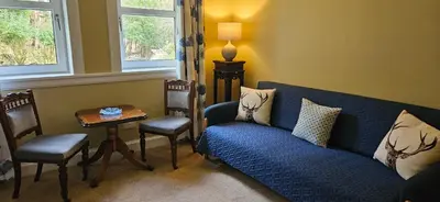 a living room with a blue couch and a table at Butt Lodge in Lochranza