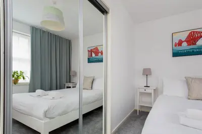 a bedroom with a mirror and a bed and a bed and a table at Modern Grassmarket Apartment in Edinburgh