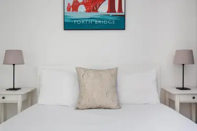 a white bed with a pillow on top of it at Modern Grassmarket Apartment in Edinburgh