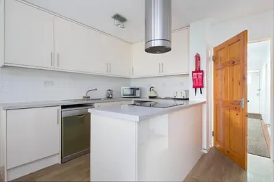 a kitchen with white cabinets and a wooden door at Modern Grassmarket Apartment in Edinburgh