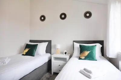 two beds in a bedroom with two mirrors on the wall at Linwater Caravan Park - Luxury Lodges and Static Caravans near Edinburgh in Newbridge