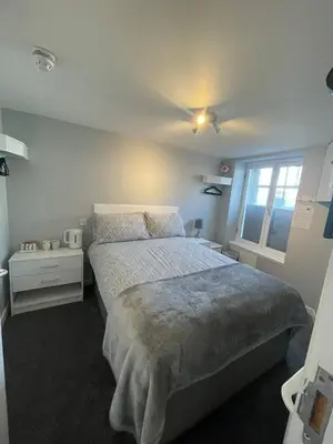 a bedroom with a large bed and a window at Black Bull with Rooms upper in Cumbernauld