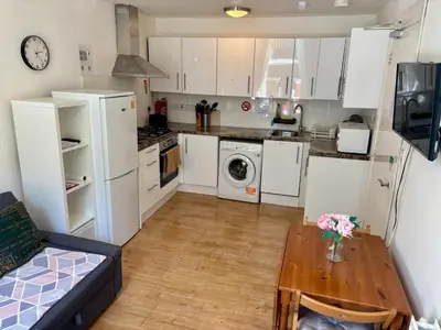a kitchen with white cabinets and a wooden table at Edinburgh Central Apartment in Edinburgh