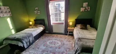 a green room with two beds and a window at Morris Terrace Apartment in Stirling