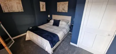 a bedroom with a bed with a blue wall at Morris Terrace Apartment in Stirling