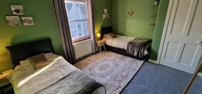 a green room with two beds and a window at Morris Terrace Apartment in Stirling