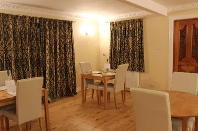a dining room with a table and chairs and curtains at Shandon Farmhouse Bed and Breakfast in Drymen