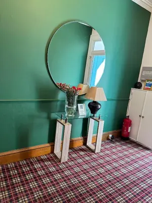 a room with a round mirror and a vase with flowers at Sandvilla Guesthouse in Oban