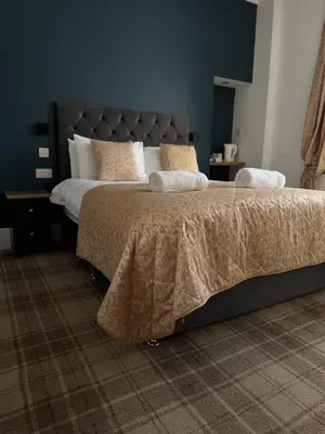 a bedroom with a large bed with a gray headboard at Sandvilla Guesthouse in Oban
